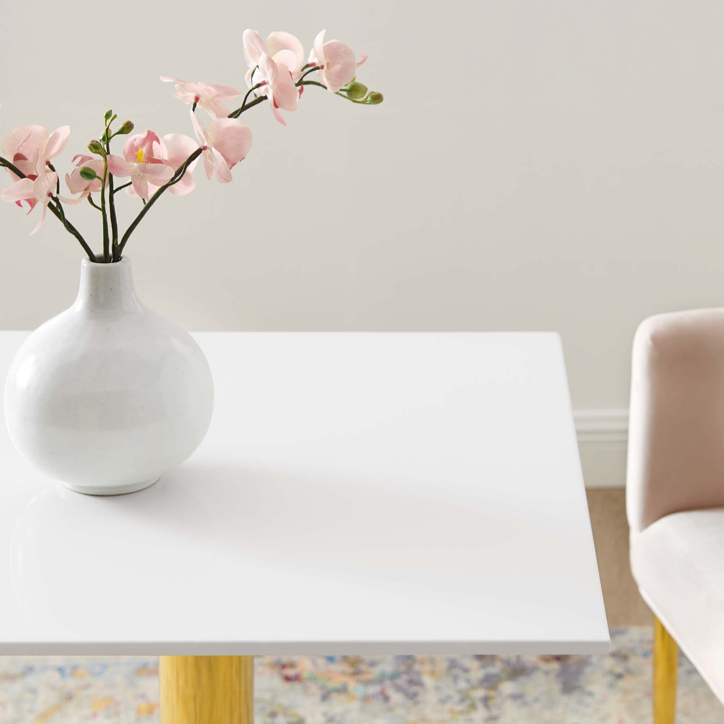 White 24-inch square dining table with a glossy surface in a bright, minimalist room.