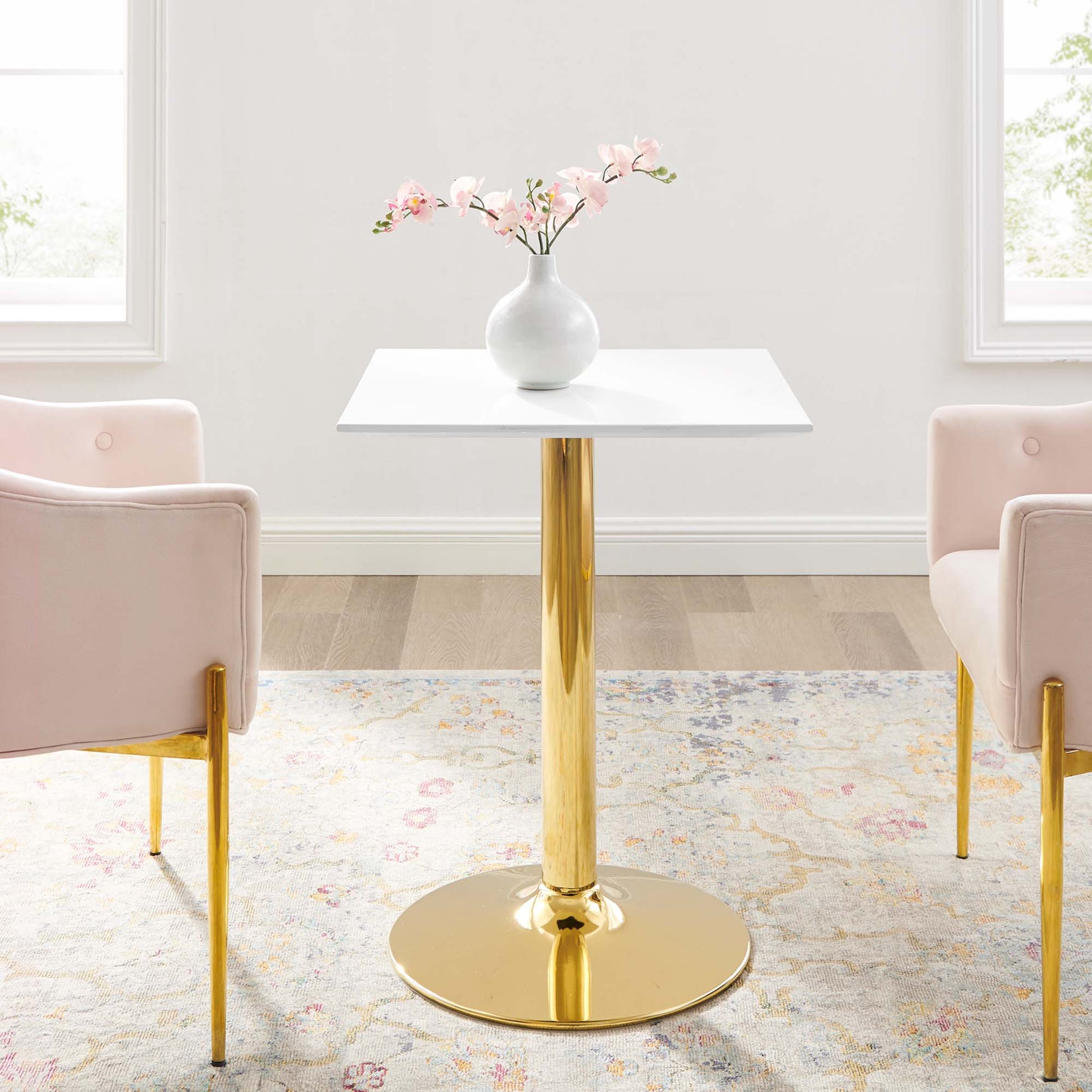 White 24-inch square dining table on a gold pedestal base with a round foot; modern glam style.