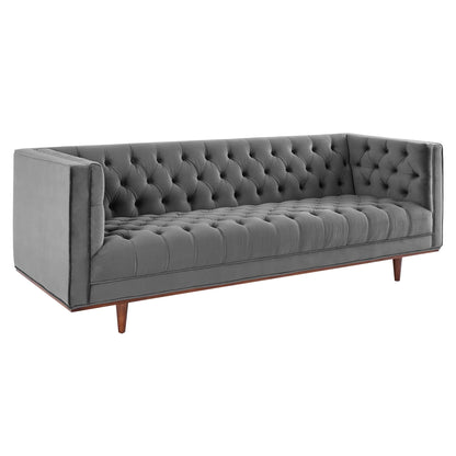 Grey velvet tufted sofa with deep button detailing, square arms, long silhouette, and tapered wooden legs.