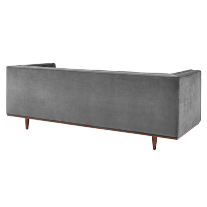 Gray tufted velvet sofa with wooden tapered legs and a long rectangular silhouette in mid-century modern style.