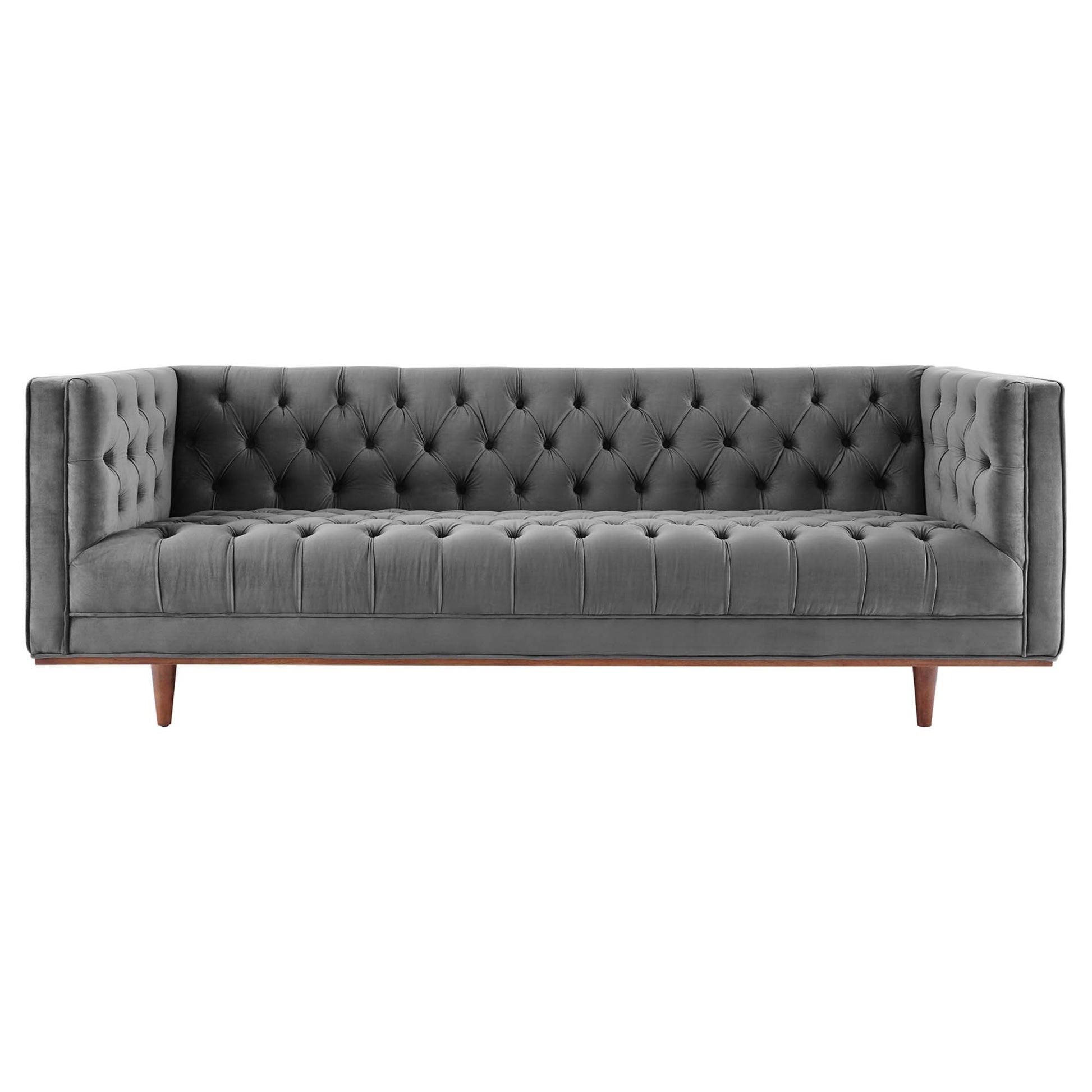 Grey velvet tufted sofa with button-tufted back, slim arms, and wooden tapered legs in mid-century style.