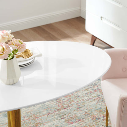 Oval 48-inch white glossy dining table with gold legs, pale pink flower vase, gold flatware, pink upholstered chair and patterned rug.