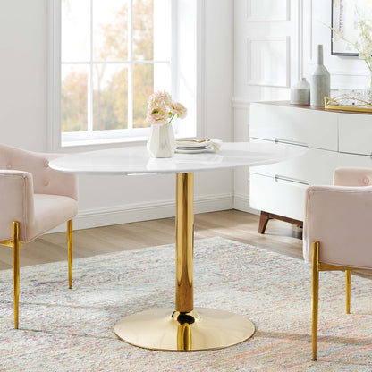 Oval white dining table with a gold pedestal base, blush pink chairs, and a vase of pink flowers.