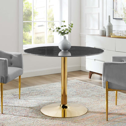 Round black marble-top table with a gold pedestal base and gray chairs in a modern glam living room.