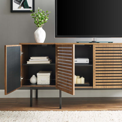 Walnut wood sideboard with black interior, slatted doors, open shelves, TV on top, white vase and greenery.