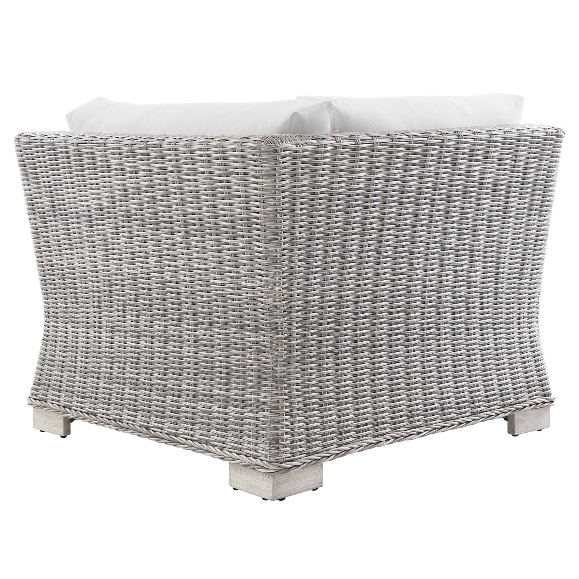 Light gray woven wicker outdoor corner chair with white cushions and pale wooden feet.