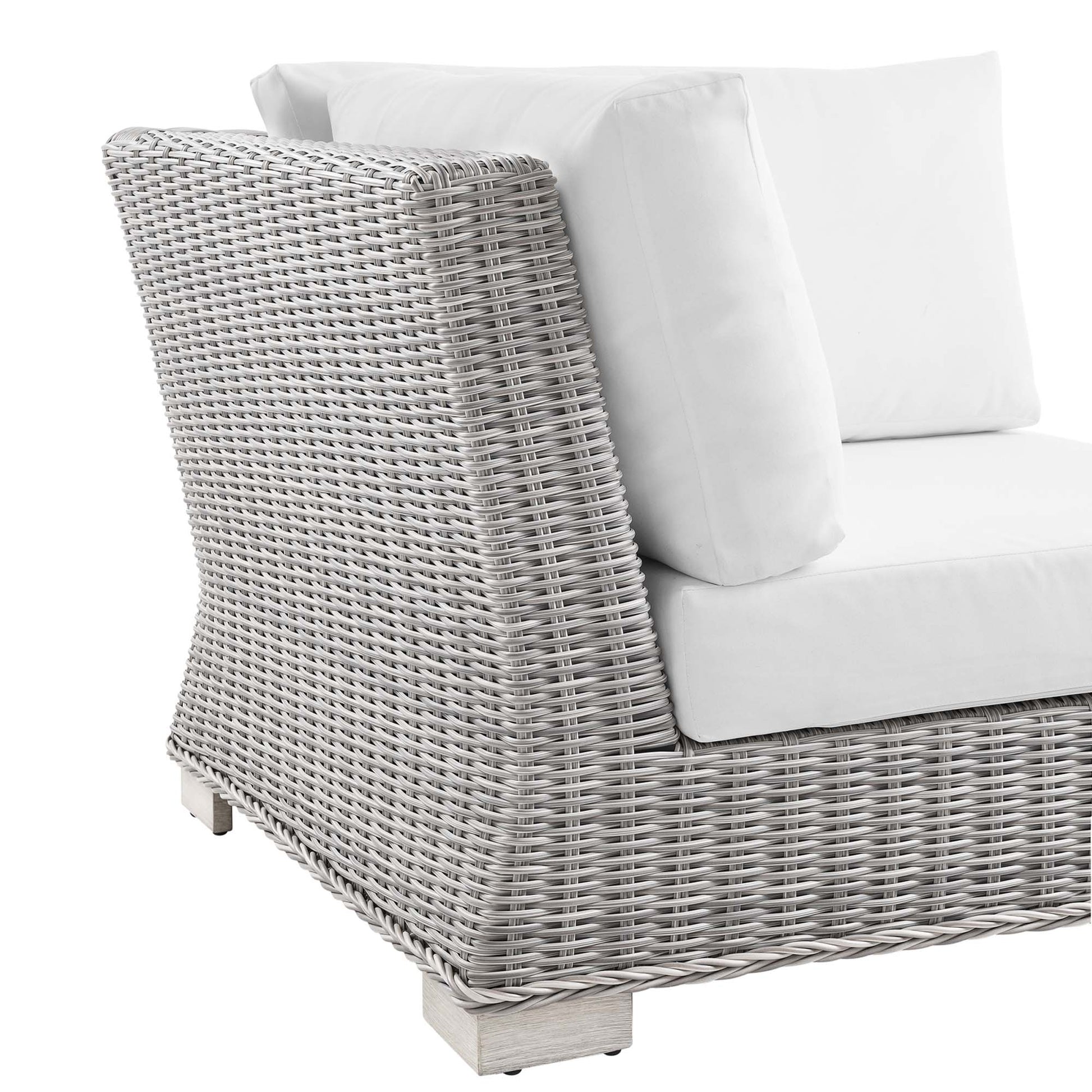 Light gray wicker outdoor corner chair with white cushions.