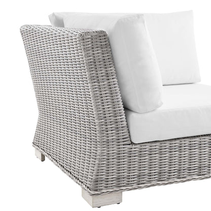 Light gray wicker outdoor corner chair with white cushions.
