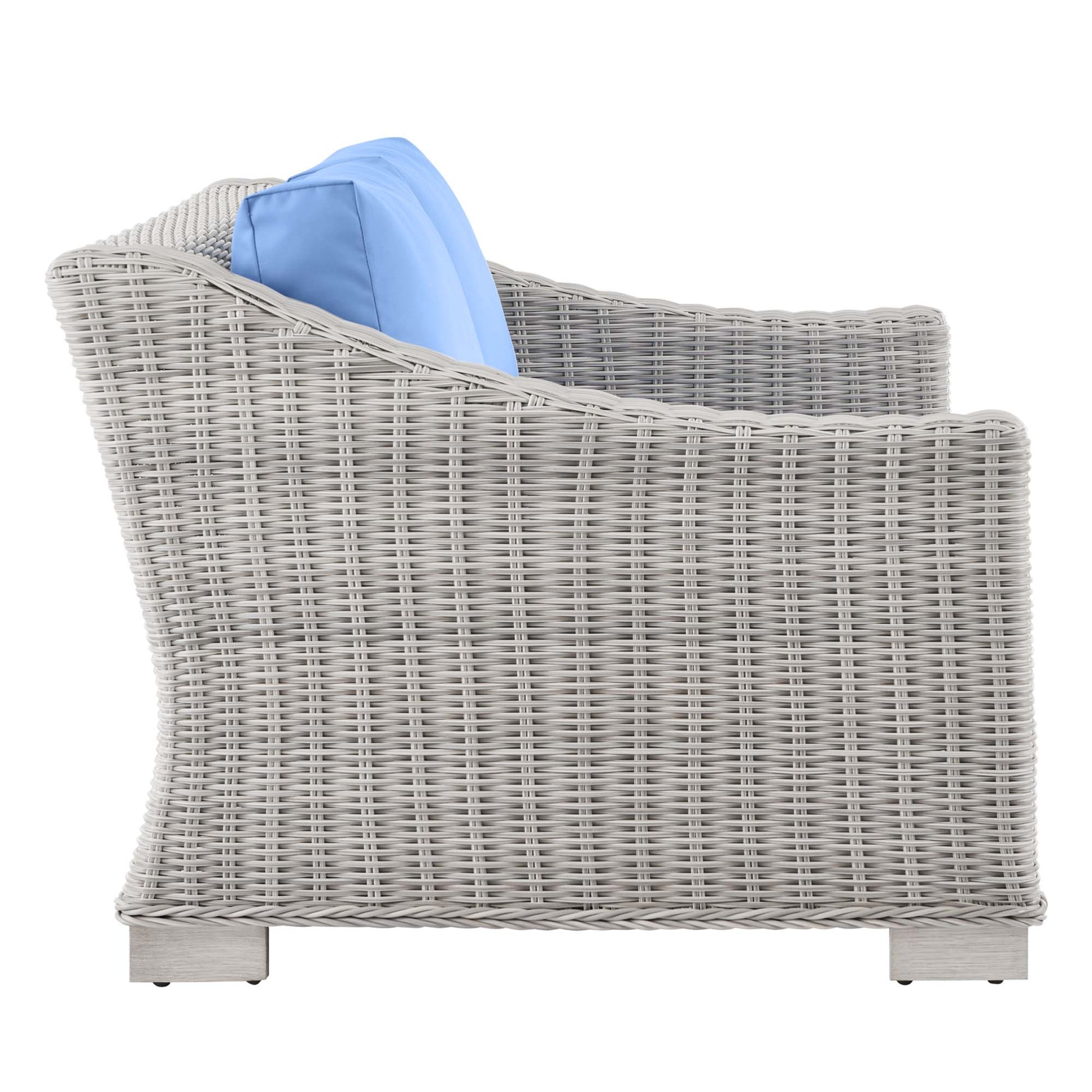 Grey wicker outdoor loveseat with blue fabric cushions, curved armrests and sturdy block legs.