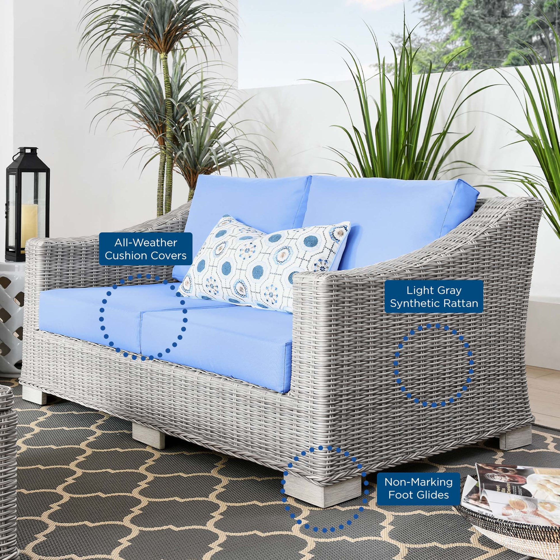 Light gray synthetic rattan loveseat with sky-blue cushions and a patterned throw pillow for outdoor patio use.