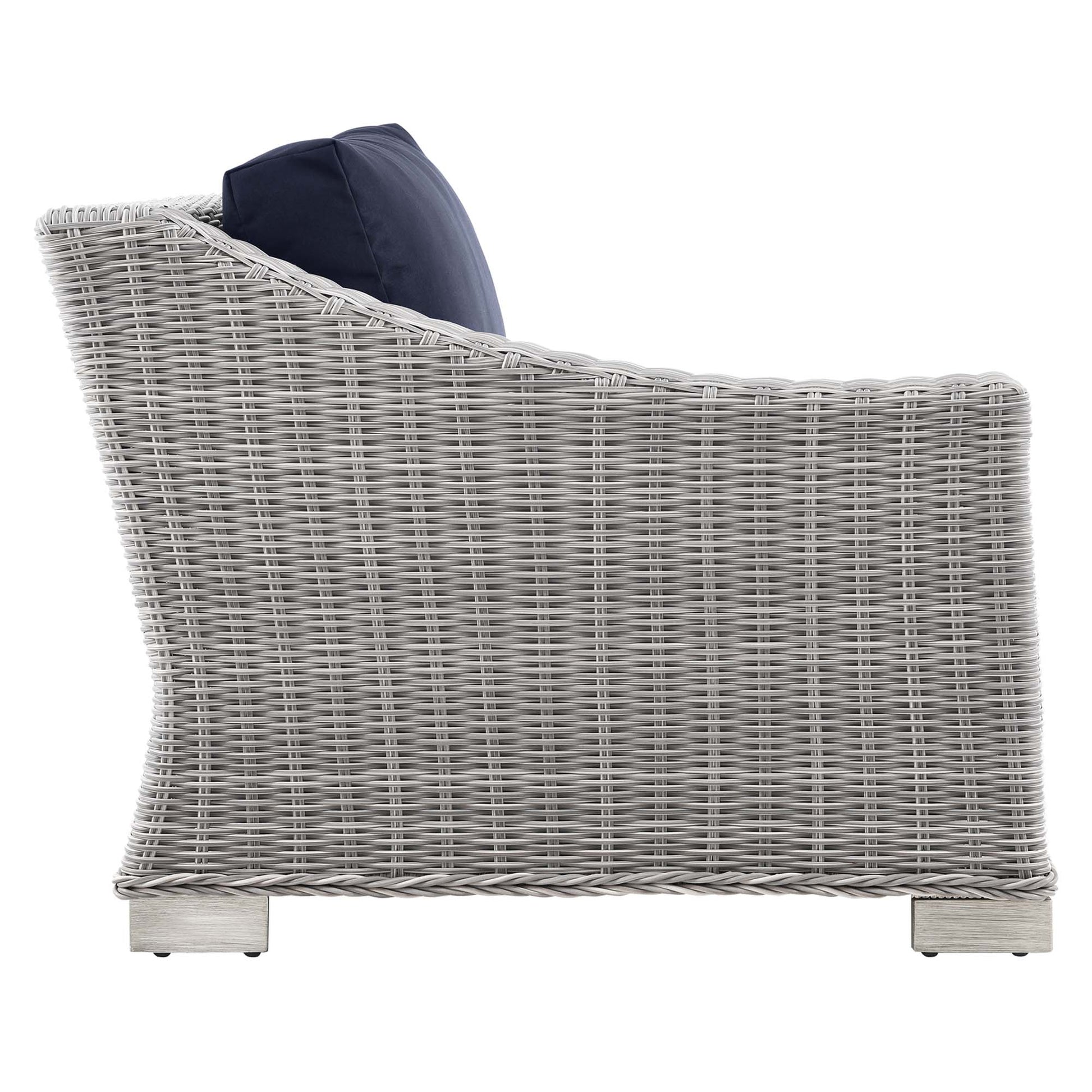 Light gray wicker outdoor left-arm chair with navy cushion, curved back and sturdy block feet.