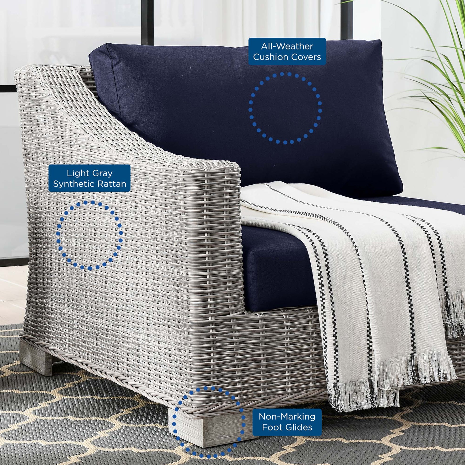 Light gray synthetic rattan outdoor armchair with navy cushions, striped throw blanket, non-marking foot glides.