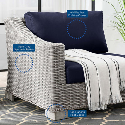 Light gray synthetic rattan outdoor armchair with navy cushions, striped throw blanket, non-marking foot glides.
