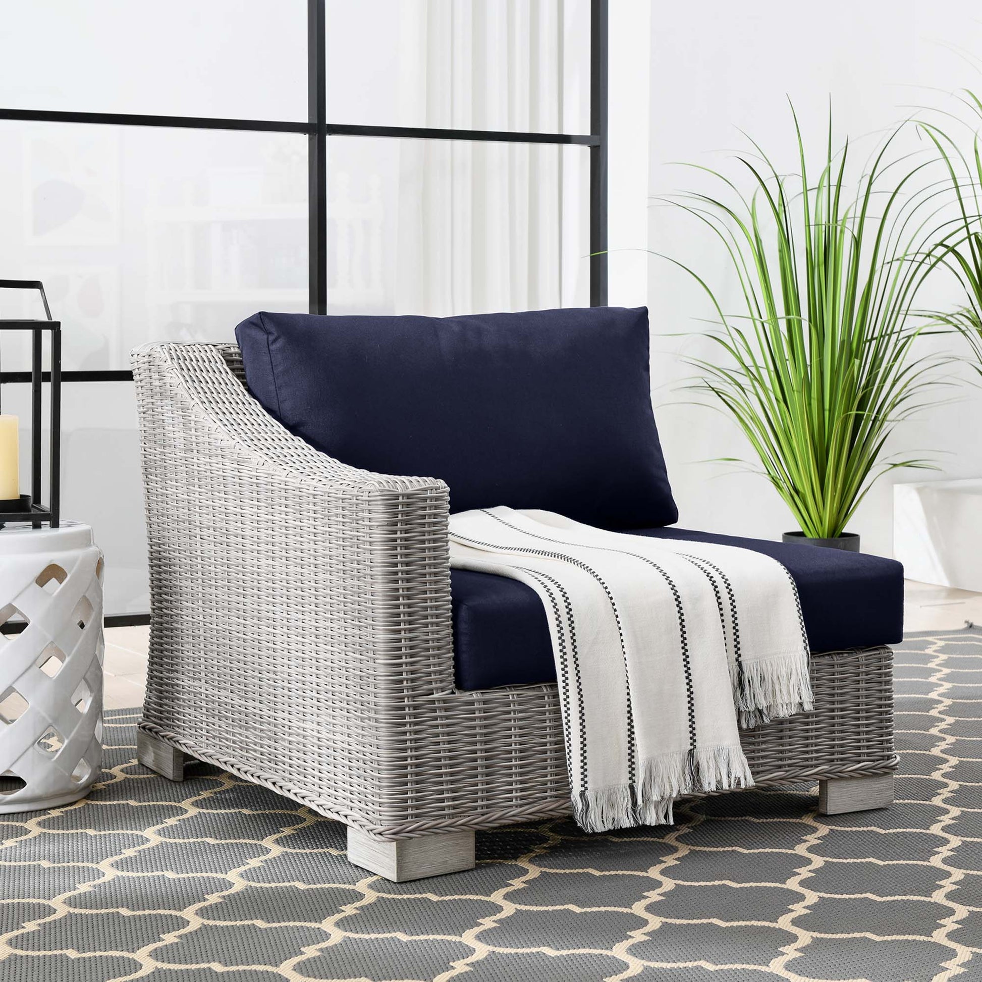 Light-gray woven rattan left-arm chair with navy cushions, outdoor patio seating.