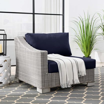 Light-gray woven rattan left-arm chair with navy cushions, outdoor patio seating.