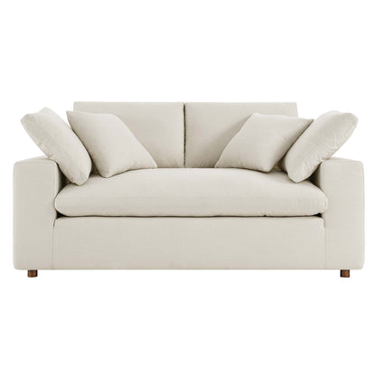 Light beige fabric loveseat with square arms and wooden feet, plush back cushions and coordinating throw pillows.