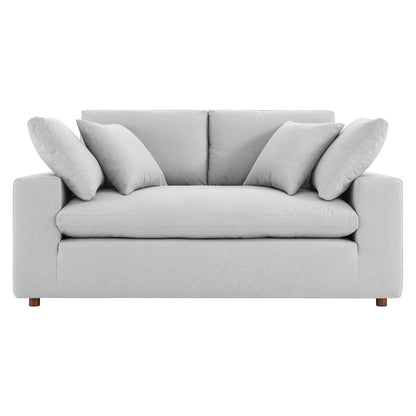 Light gray fabric loveseat with wide squared arms, two back cushions, several decorative pillows & wooden legs.