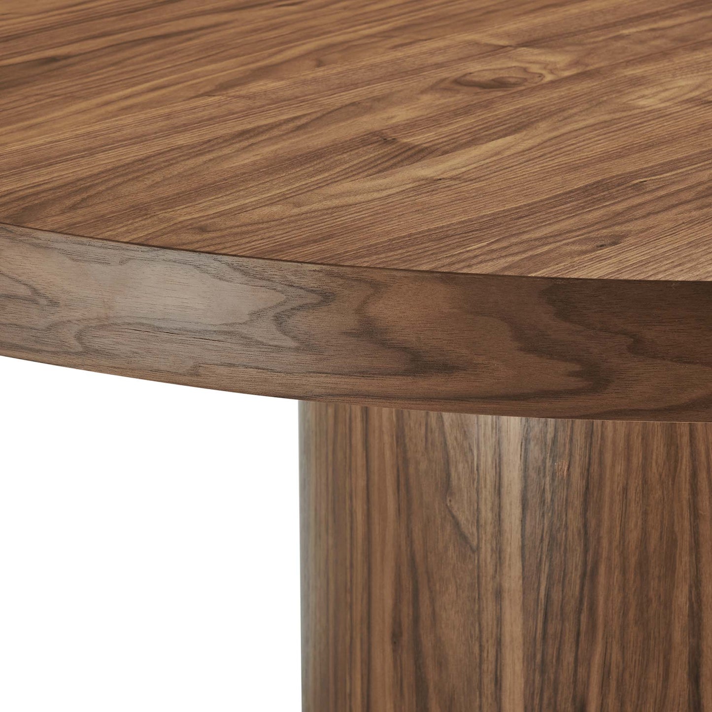 Round walnut wood dining table with curved edge and single pedestal leg, warm natural grain.
