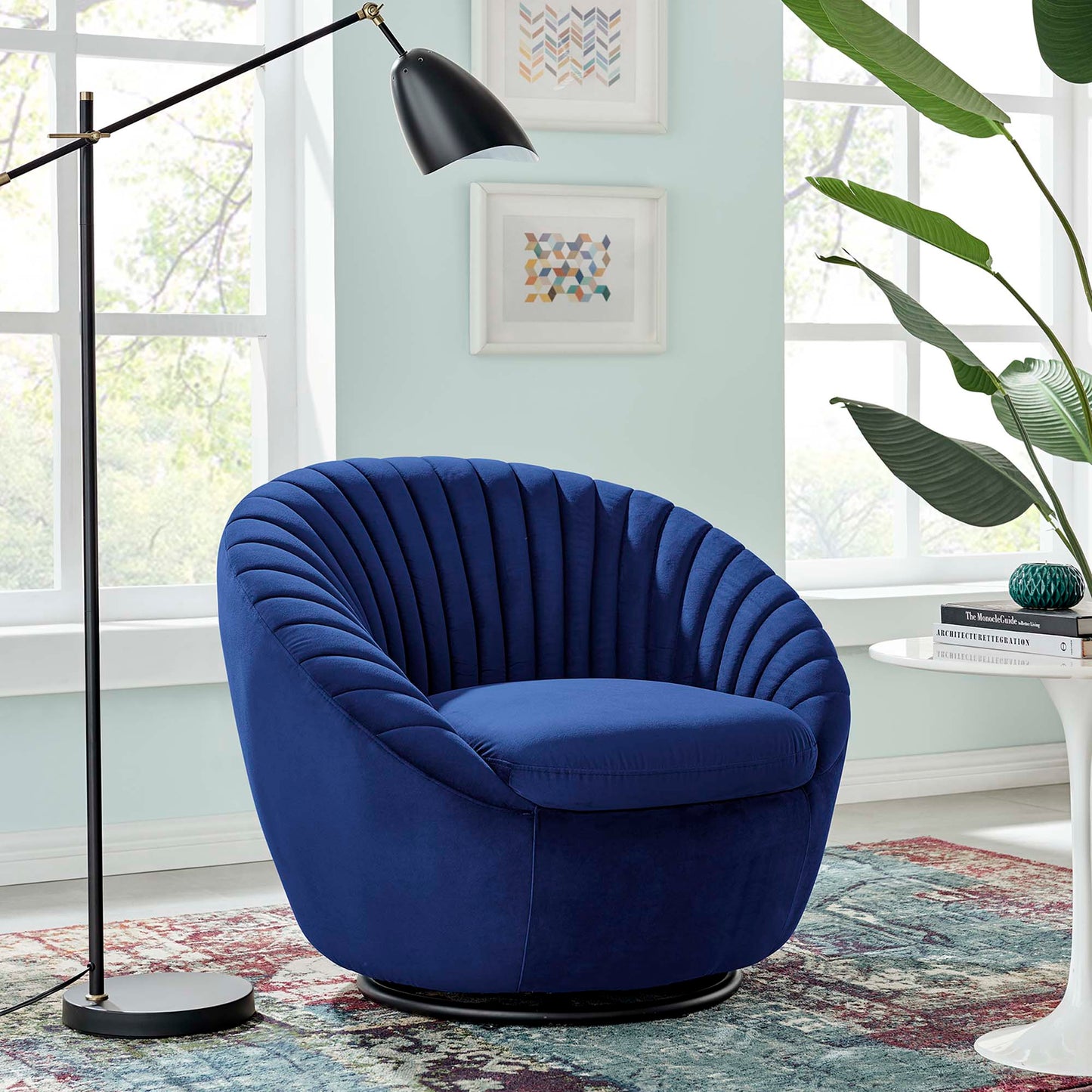 Navy velvet round swivel lounge chair with pleated back in a mint living room, black base, with plant and arc lamp.