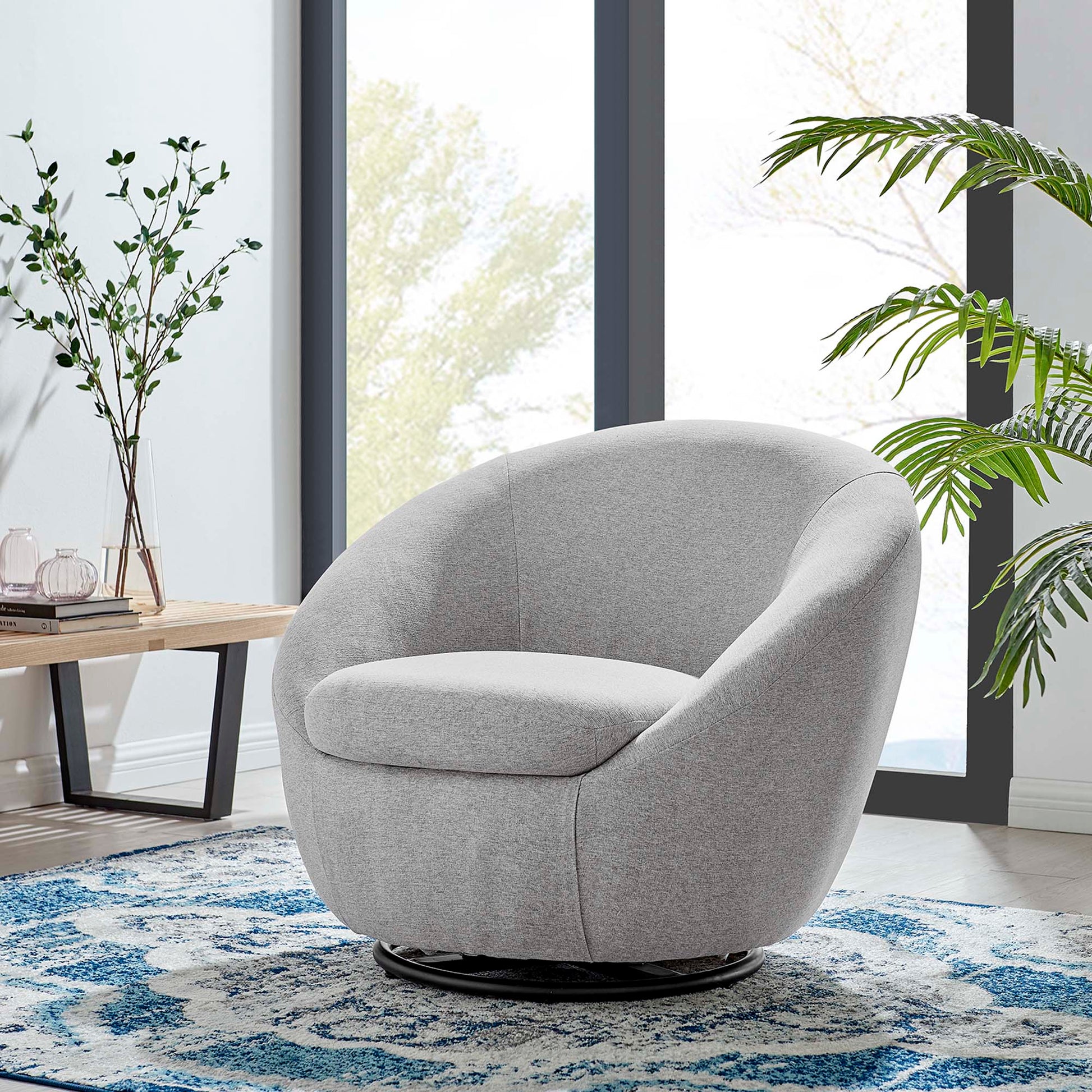 Light gray rounded fabric swivel lounge chair with a circular base in a modern living room.