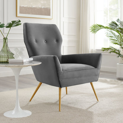Gray velvet mid-century armchair with button-tufted back and gold tapered legs in a bright living room.