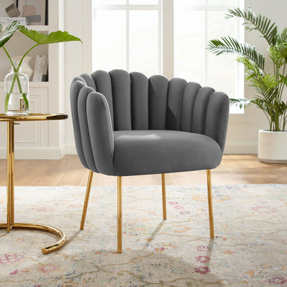Gray velvet channel-tufted armchair with gold legs in a bright living room.