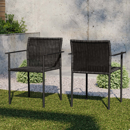 Two dark wicker outdoor armchairs with metal frames on a grassy patio against a concrete wall.