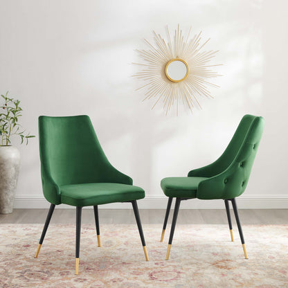 Pair of emerald green velvet dining side chairs with black legs and gold tips, set against a sunburst mirror.