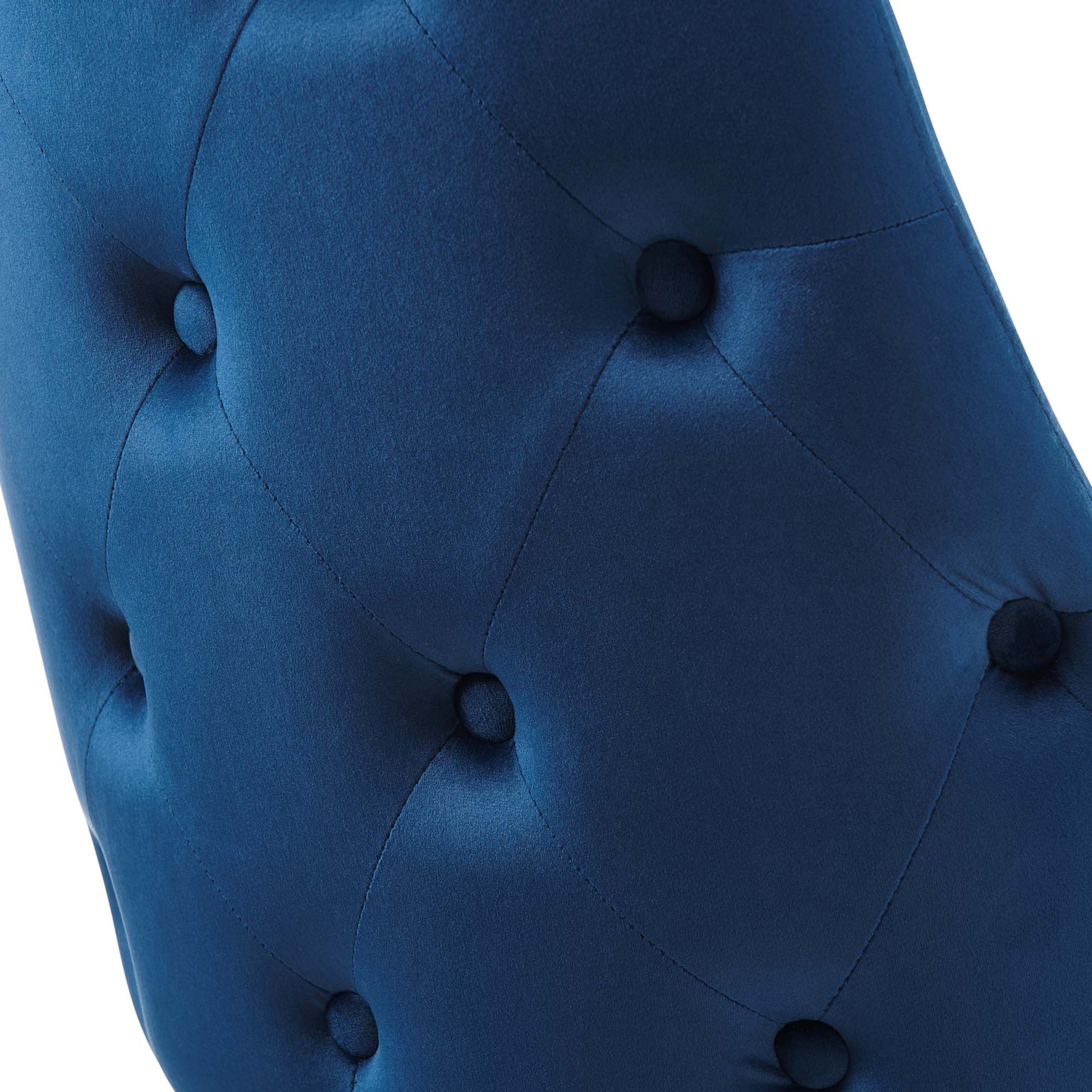 Close-up of navy blue tufted velvet upholstery with round buttons in a diamond pattern.