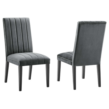 Pair of dark gray velvet dining chairs with vertical channel tufting, nailhead trim along edges, tapered legs.