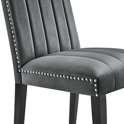 Gray velvet upholstered dining chairs with vertical channel tufting, nailhead trim along edges & dark wood legs.