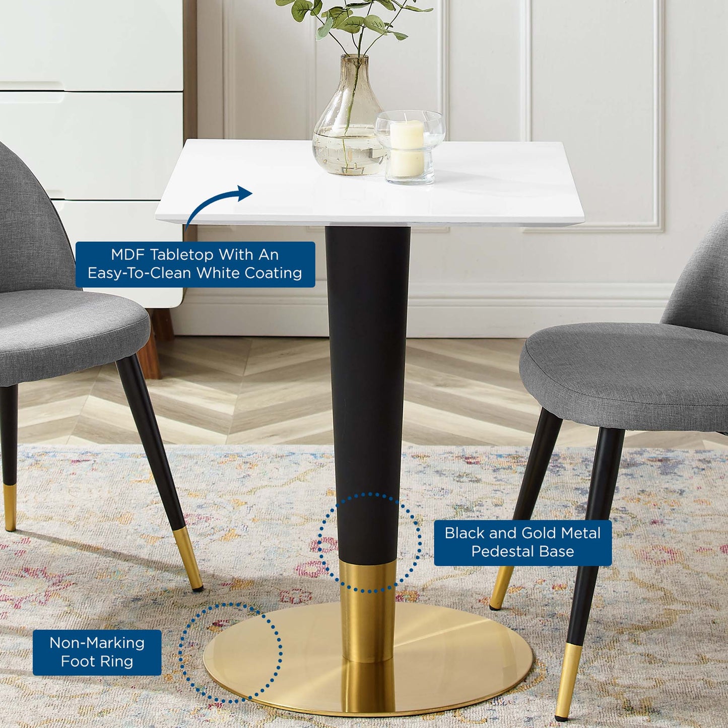 White MDF square dining table with a black & gold pedestal base; gray upholstered chairs with black legs and gold tips.