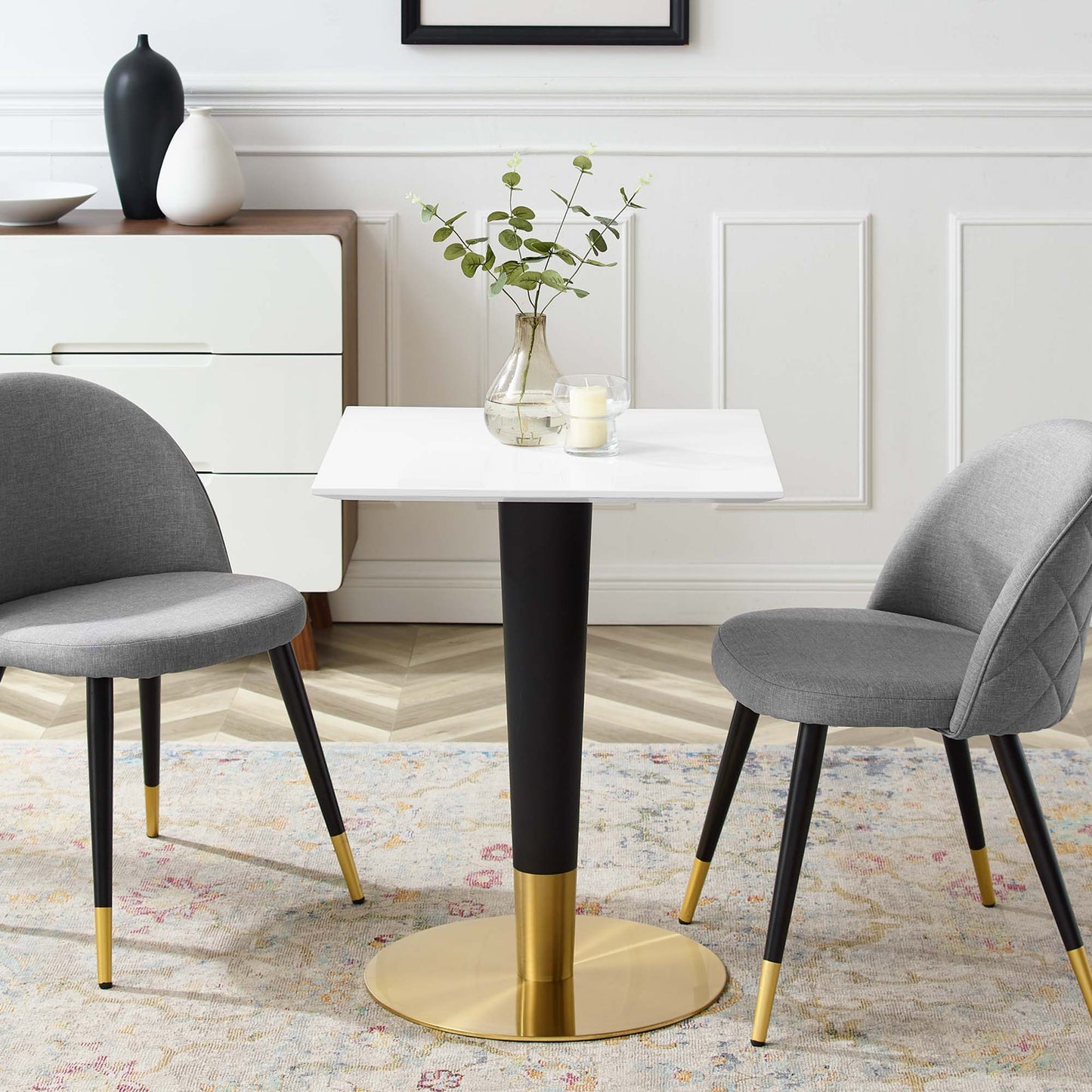 White 24" square dining table with a black pedestal stem and a gold round base.