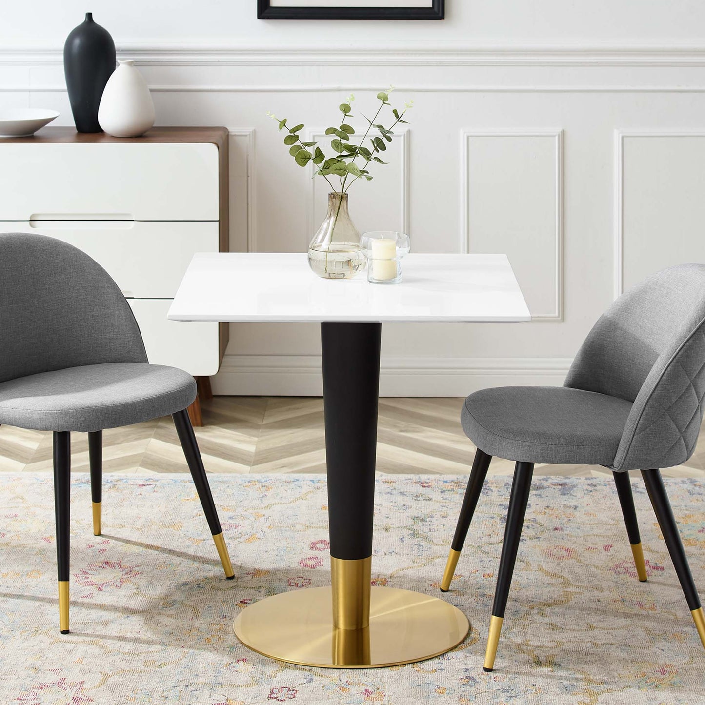 White square dining table on a black-and-gold pedestal base with gray upholstered chairs, gold-tipped legs; dining set.