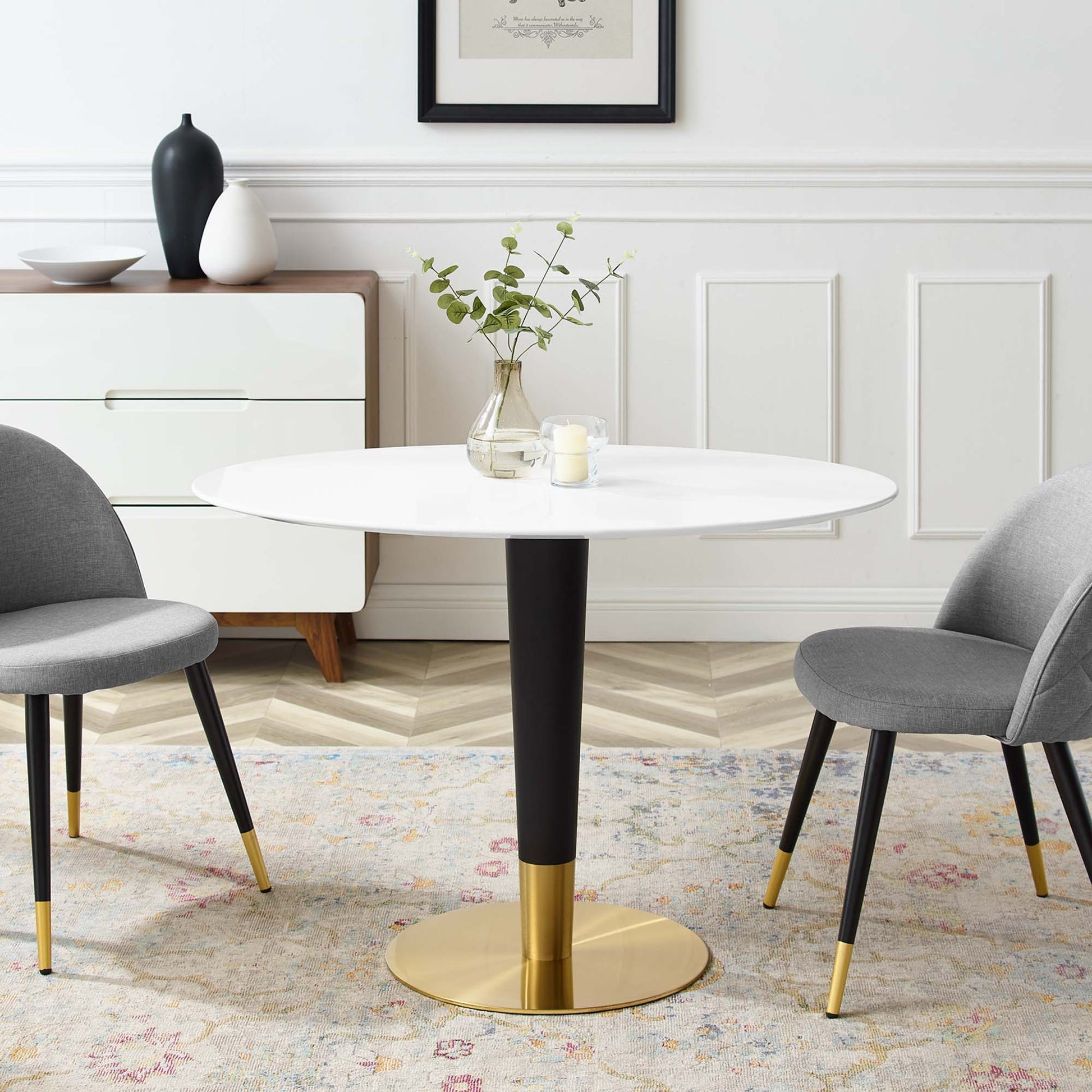 Oval dining table with white top and gold pedestal base; gray upholstered dining chairs.