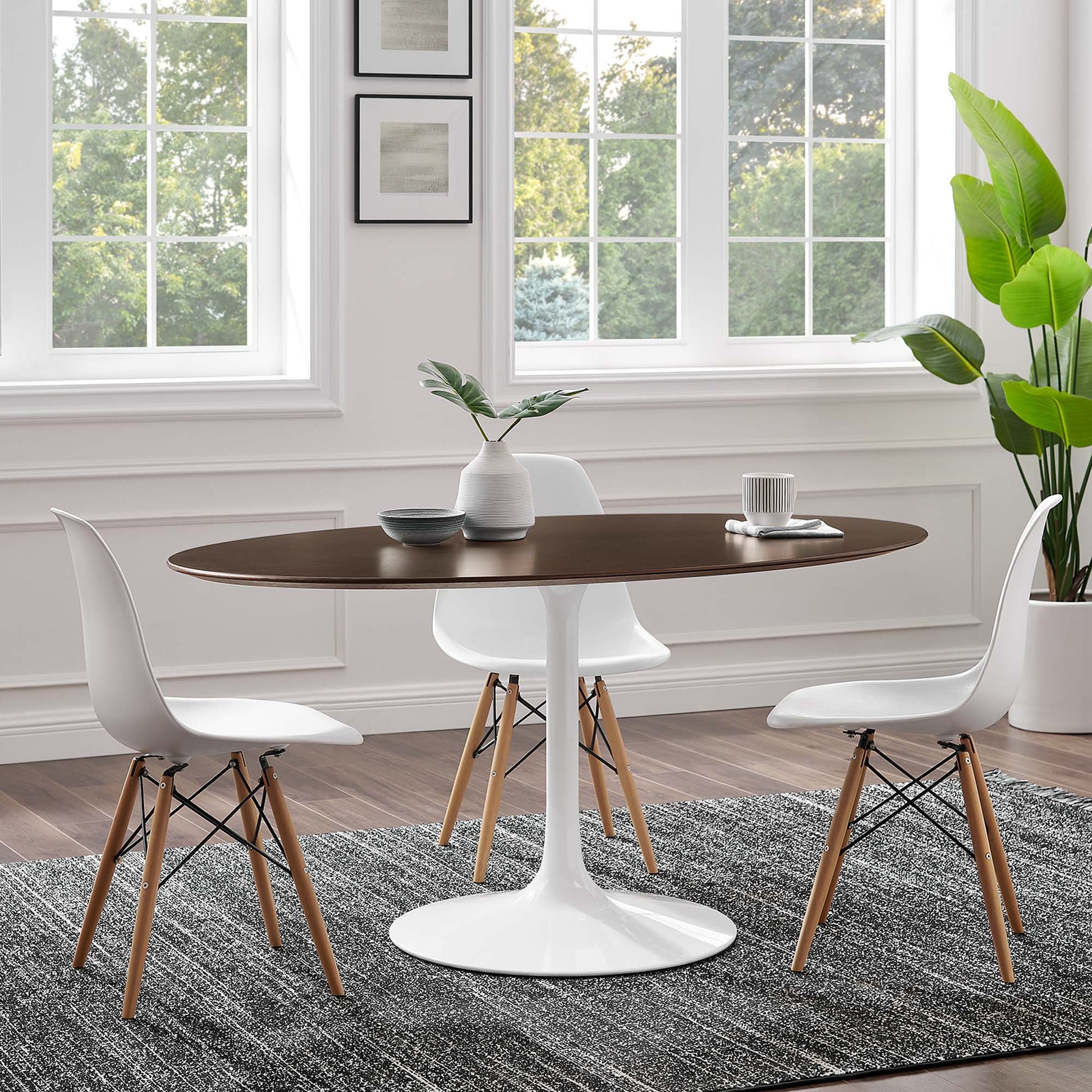 Oval cherry walnut wood dining table, surrounded by white molded chairs with wooden legs on a gray rug.
