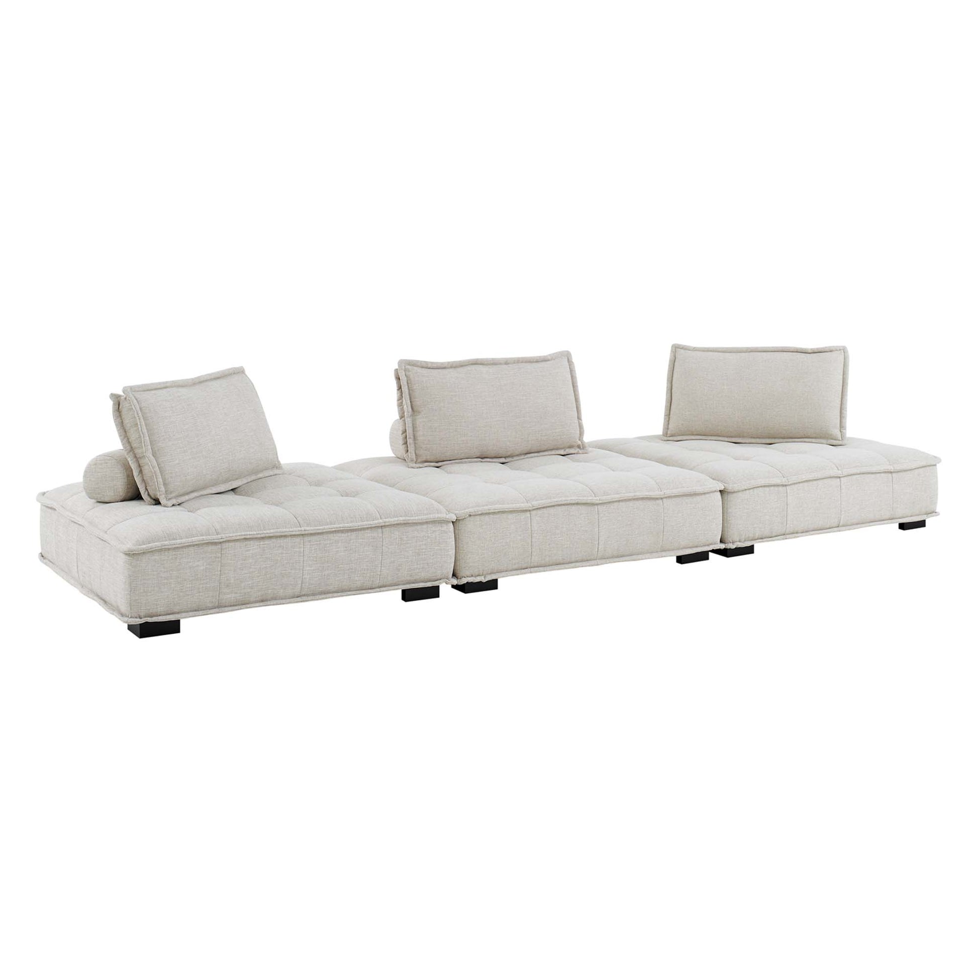 Beige tufted fabric modular sectional sofa with low black legs, three-seat layout and cylindrical bolster pillow.