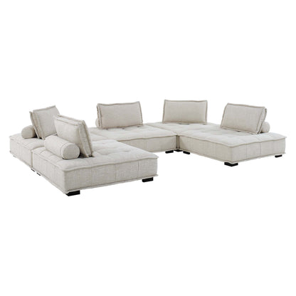 Beige tufted fabric sectional sofa in an L-shape with loose back cushions and cylindrical bolsters.
