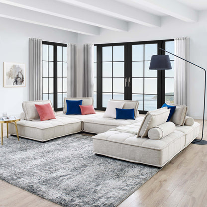 Brown modular sectional with chaise in a living room; tufted fabric upholstery, black-framed windows, and a curved blue floor lamp.