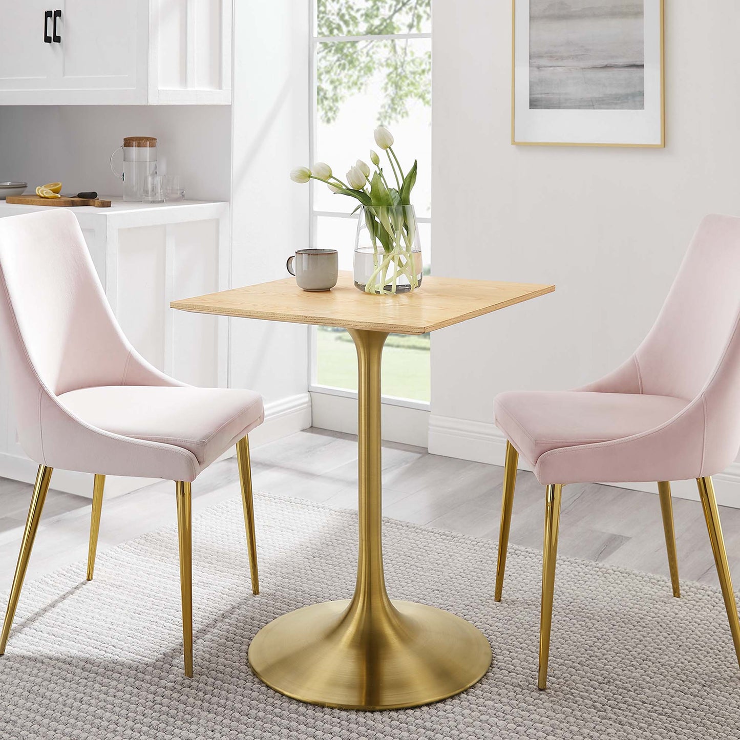 24" square brown wood dining table on a gold pedestal base, pink upholstered chairs with gold legs; tulips and mug centerpiece.