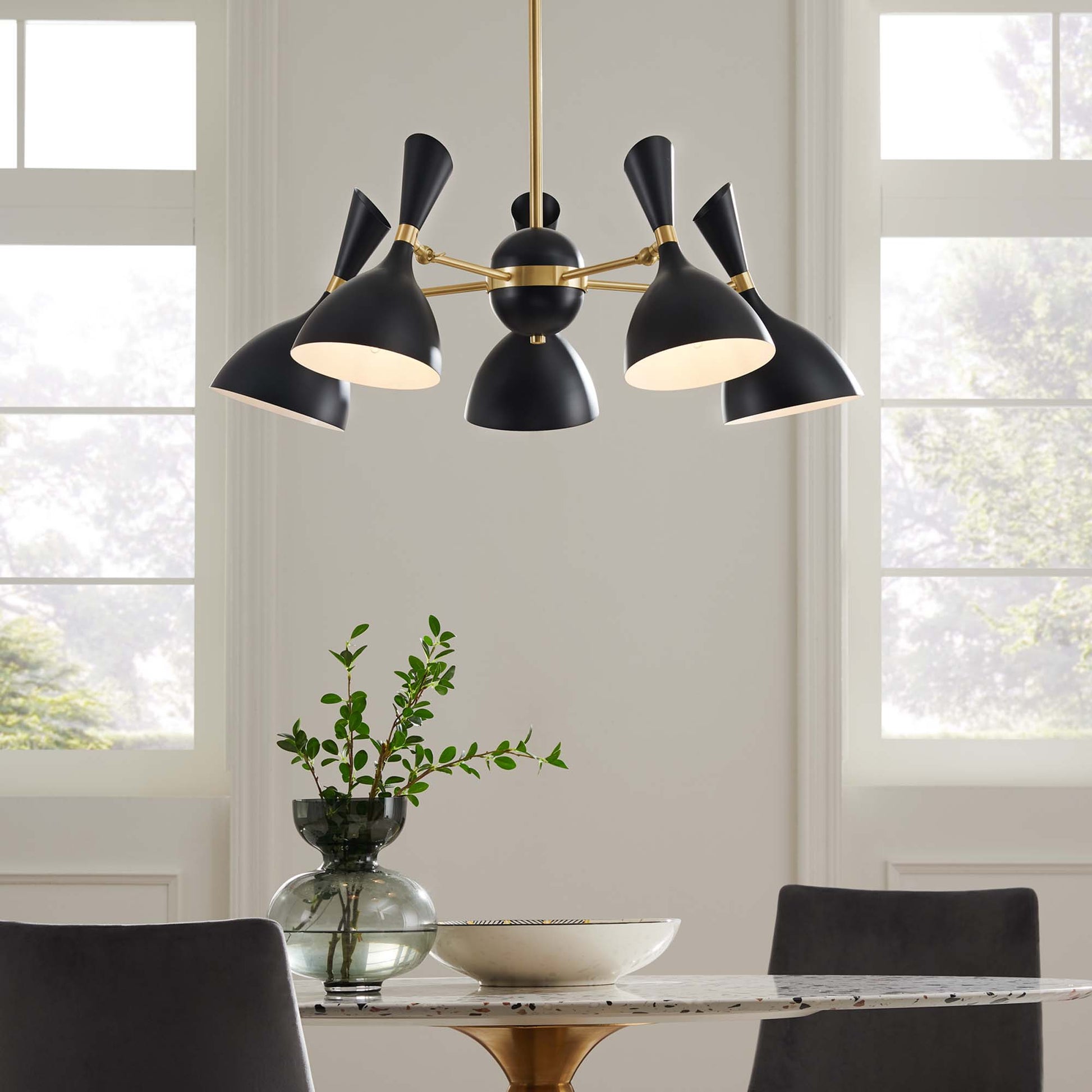 Black cone-shade chandelier with brass arms and central sphere, five-light pendant over a marble dining table.