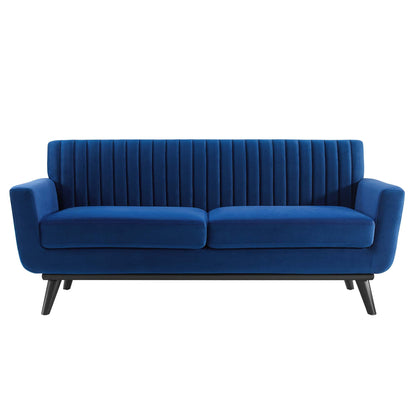 Navy blue velvet loveseat with vertical channel tufting on back, two-seat cushions, and black angled legs.