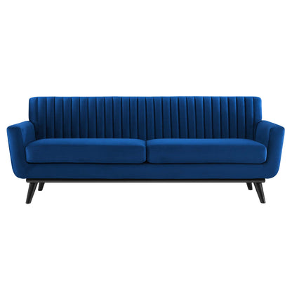 Navy blue velvet sofa with vertical channel tufting, two seat cushions and angled mid-century legs.
