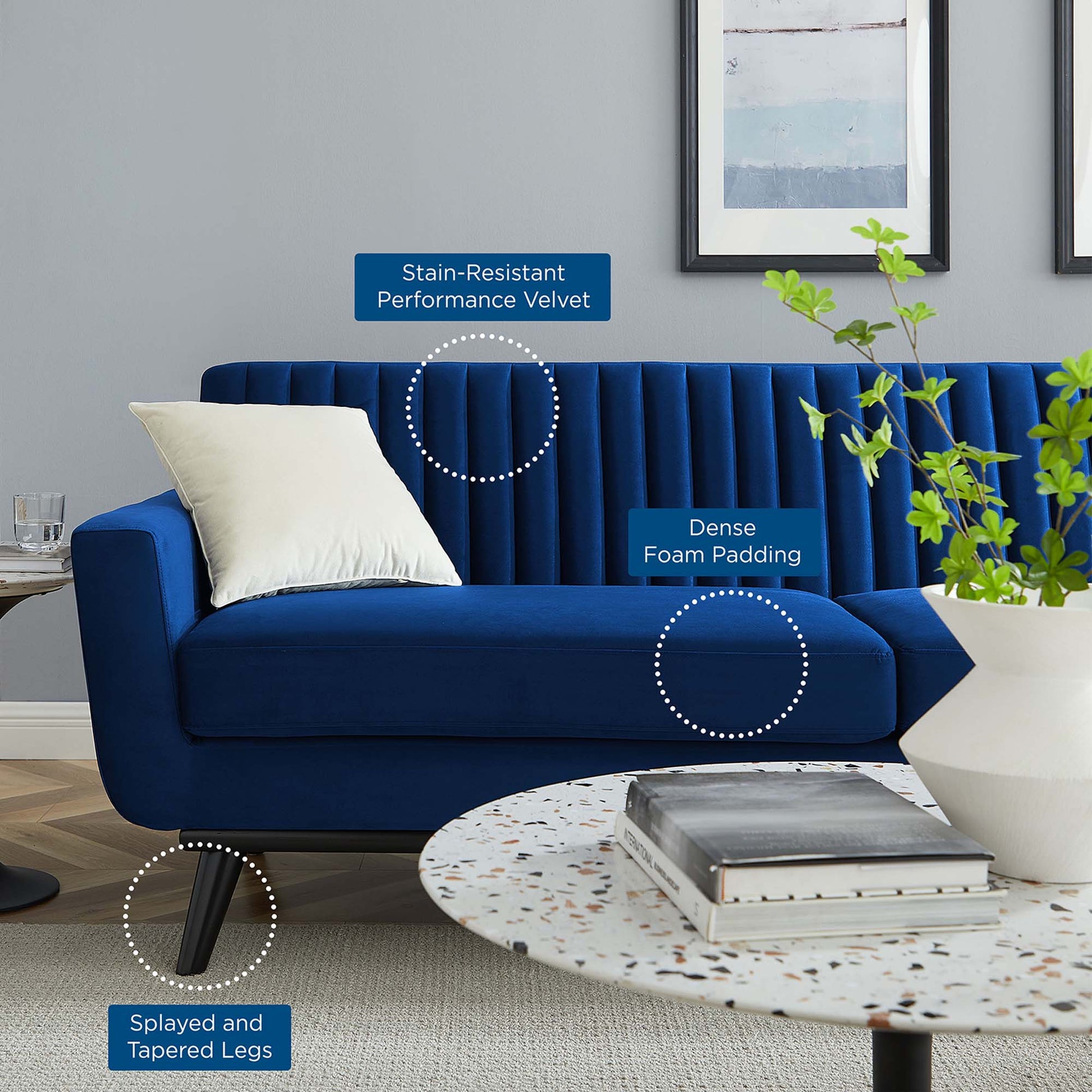 Navy blue velvet sofa with channel-tufted back, dense foam padding, and splayed painted legs in a modern living room.