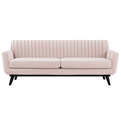 Blush pink velvet sofa with vertical channel tufting, two cushions, black angled legs.