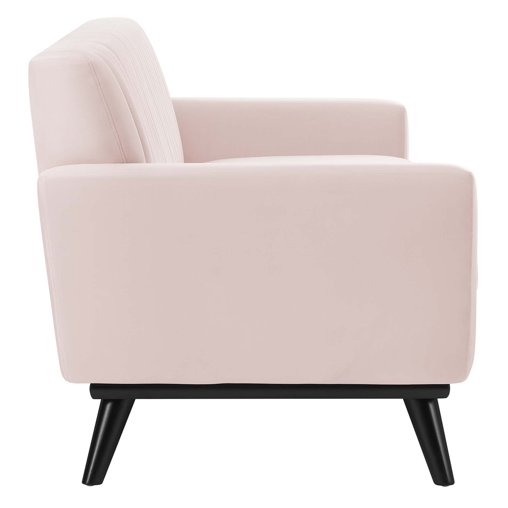 Pink velvet sofa with channel tufting, cushioned back and arms on black angled legs, mid-century modern style.