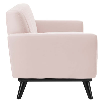 Pink velvet sofa with channel tufting, cushioned back and arms on black angled legs, mid-century modern style.