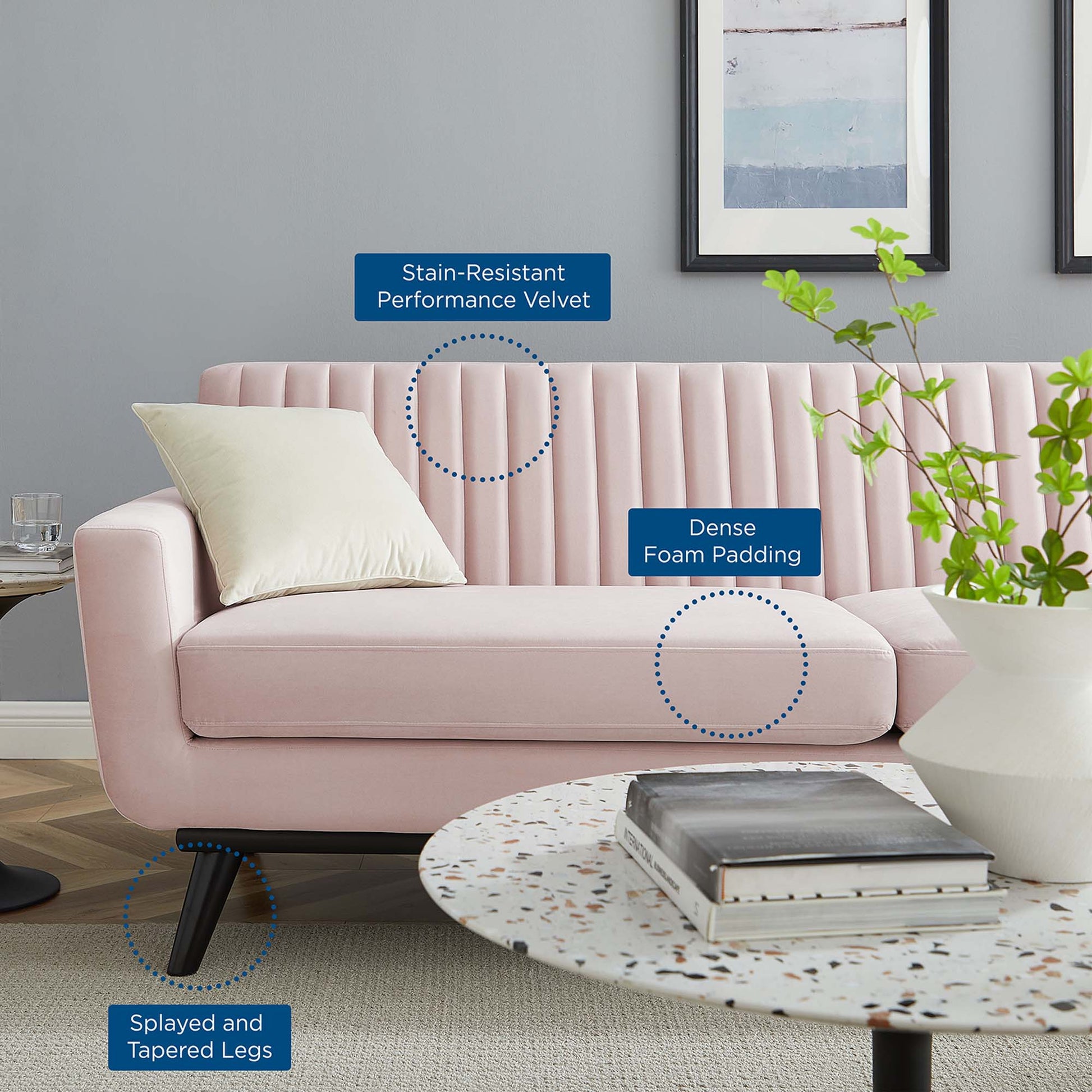 Pink velvet sofa with vertical channel tufting, dense foam padding, splayed tapered legs, pillow.