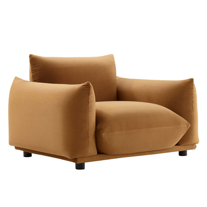 Caramel brown velvet fabric armchair with thick square cushions, low boxy silhouette and short black feet.