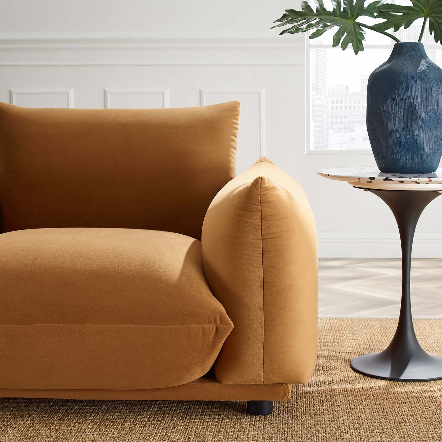 Cognac velvet armchair with rounded arm and plush back cushion in a modern mid-century living room.